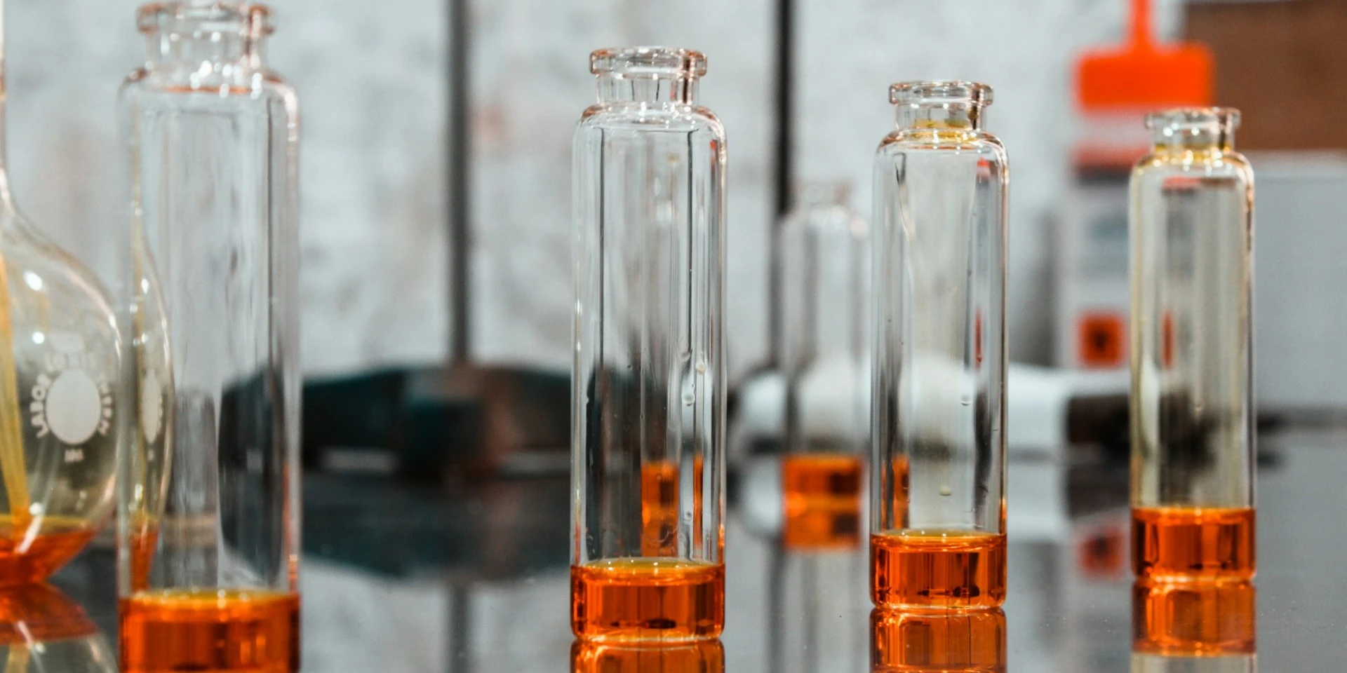 Flacons de parfum dans un laboratoire illustrant la création des notes olfactives de tête, cœur et fond.