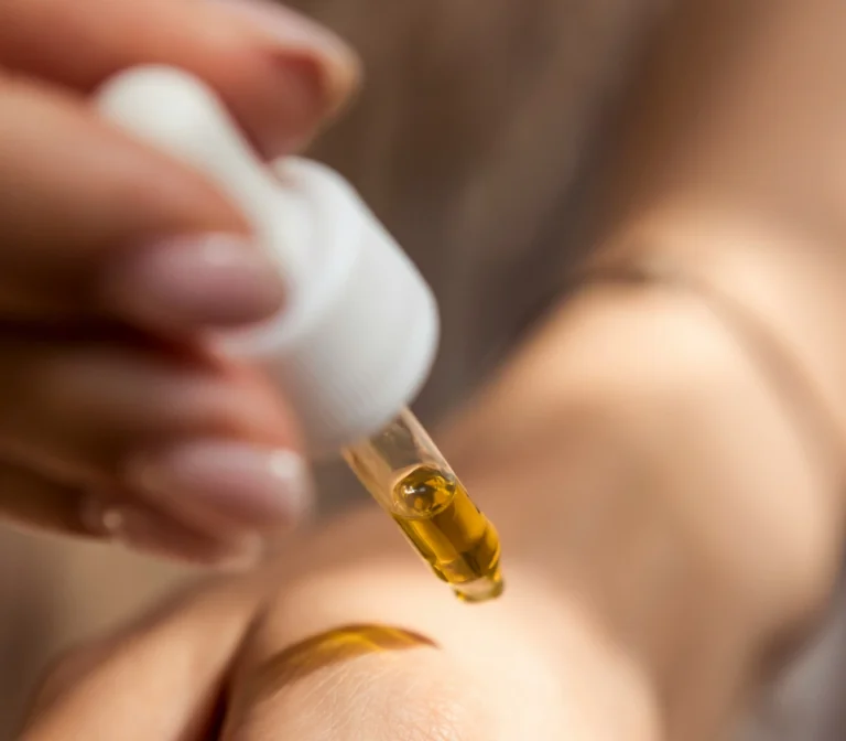 Application d’un concentré parfumé sur la peau avec une pipette, symbole d’extrait de parfum et de notes intenses.