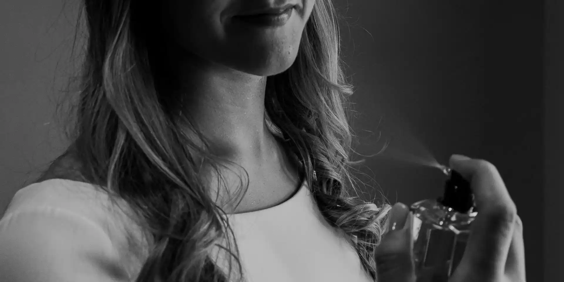 Une femme s'applique du parfum dans le cou